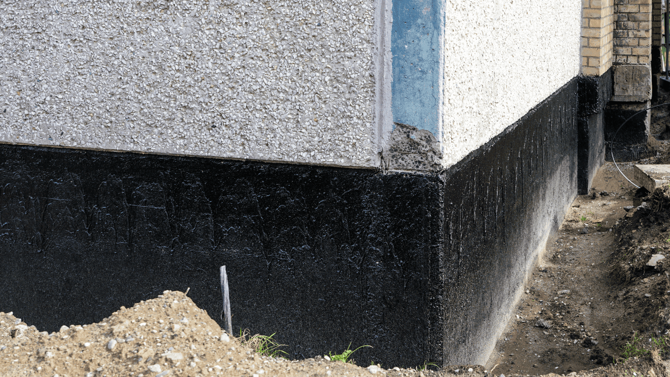 Black damp-proof tanking coating applied to an exterior foundation wall