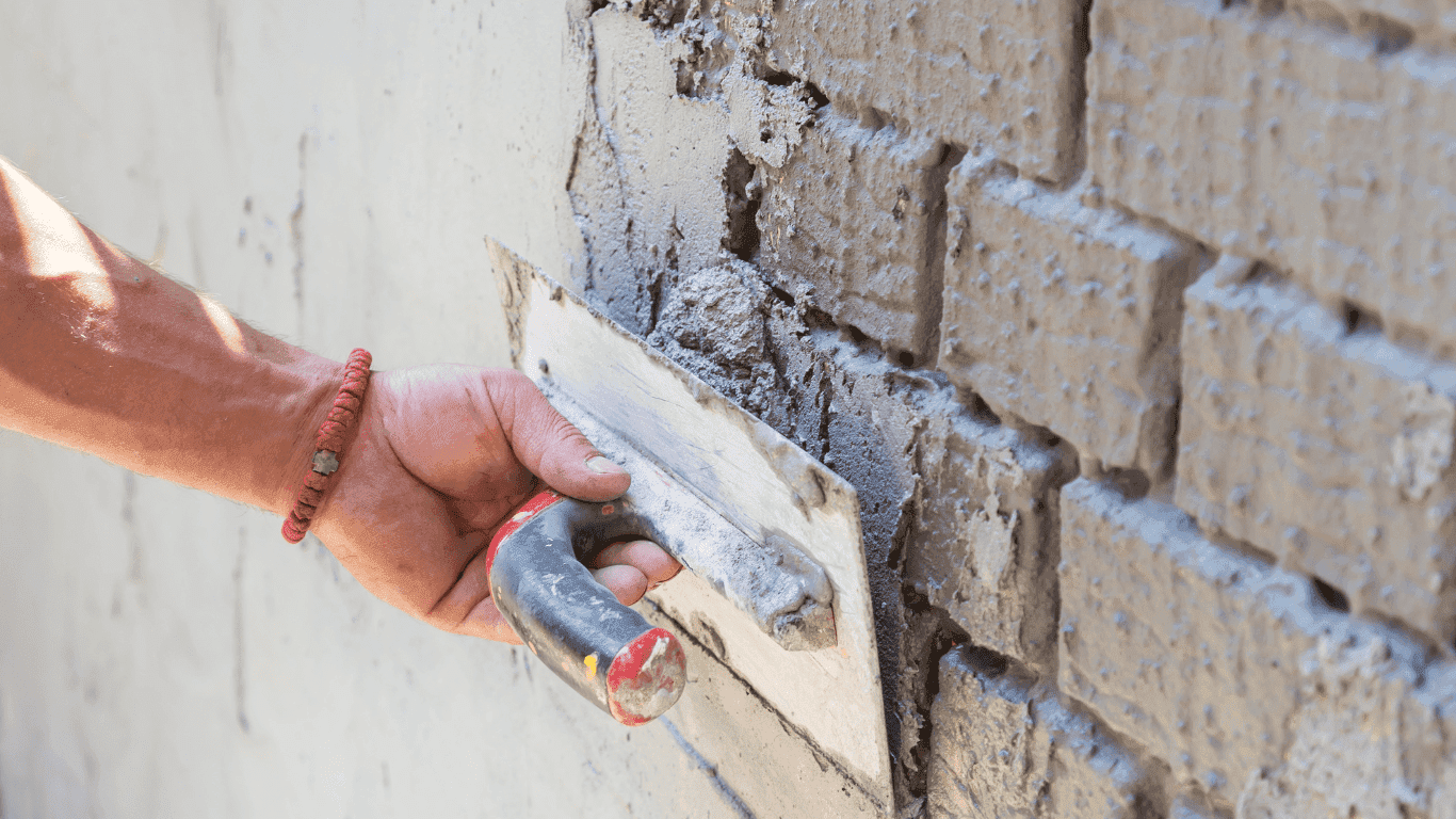 G Lee Plastering applying a render coat to an exterior brick wall